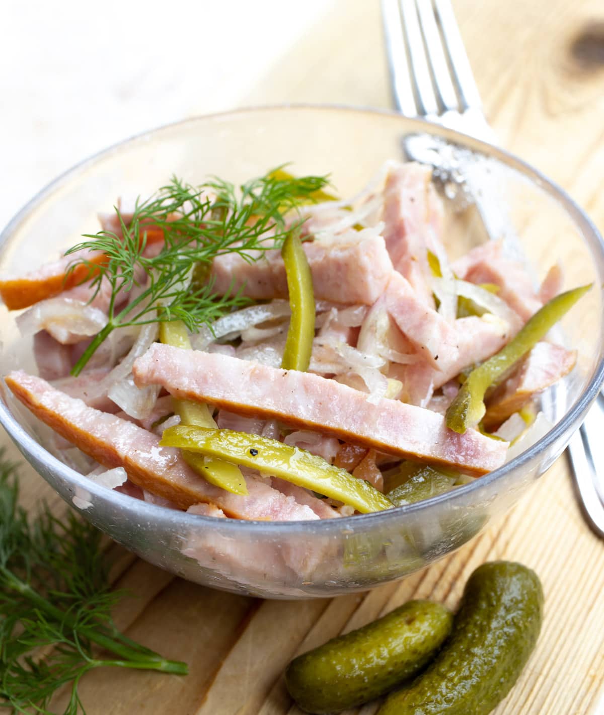 A salad made with sliced sausage, pickles, onion and topped with fresh dill.