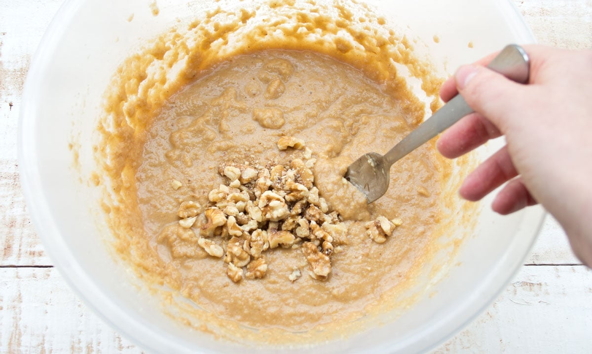 Stirring crushed walnuts into the batter with a fork.