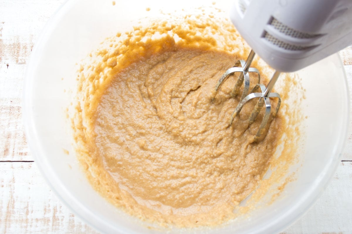 Banana batter in a bowl and an electric mixer.