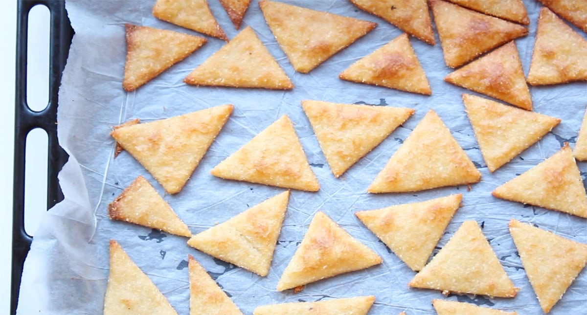 Baked tortilla chips on a parchment paper-lined baking sheet.