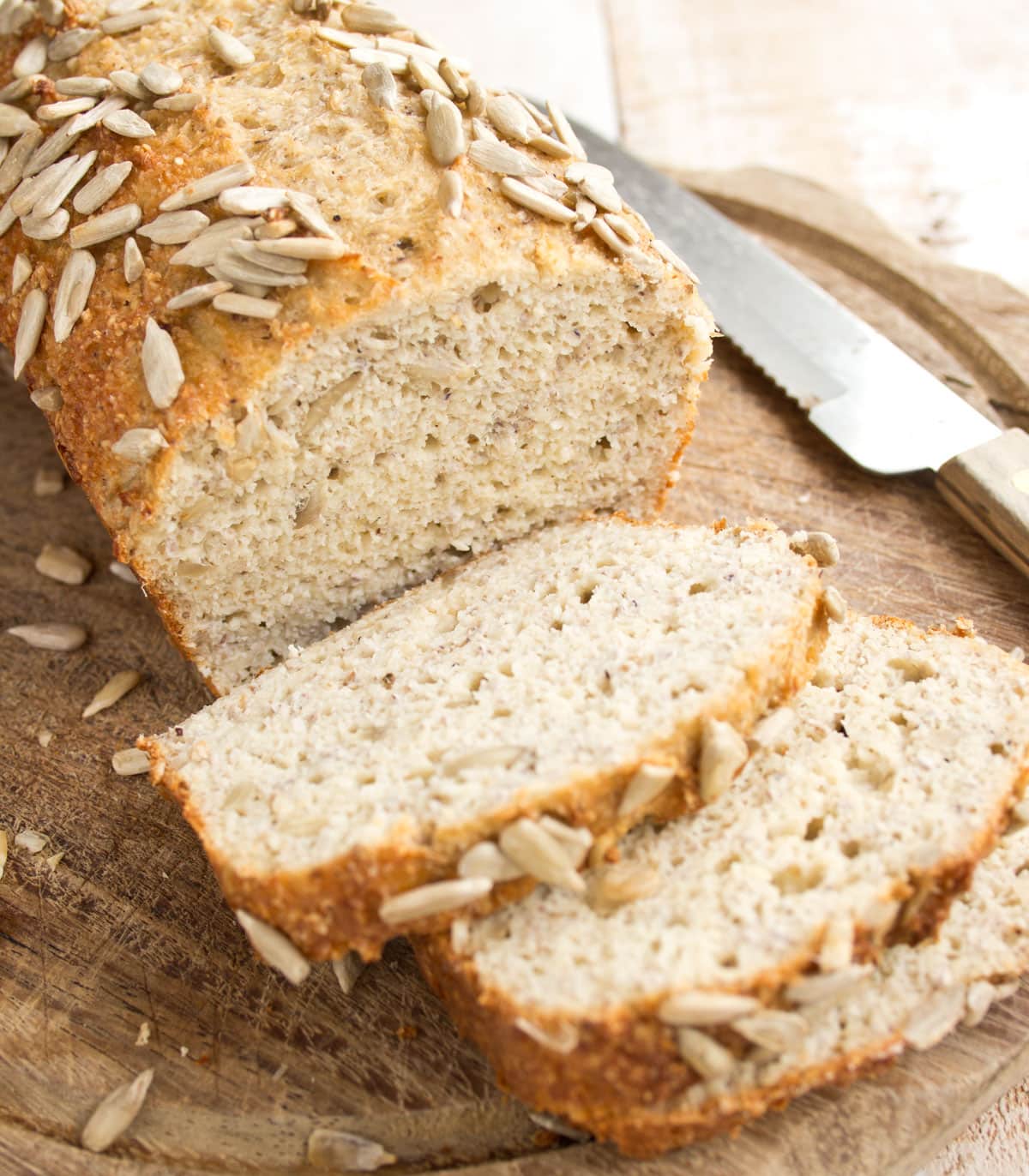 A loaf of bread with 3 slices and a knife.