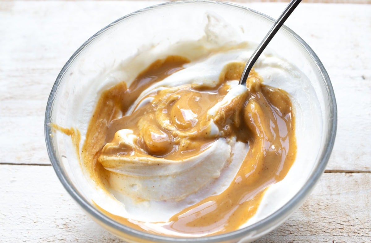 Combining peanut butter and yogurt in a bowl.