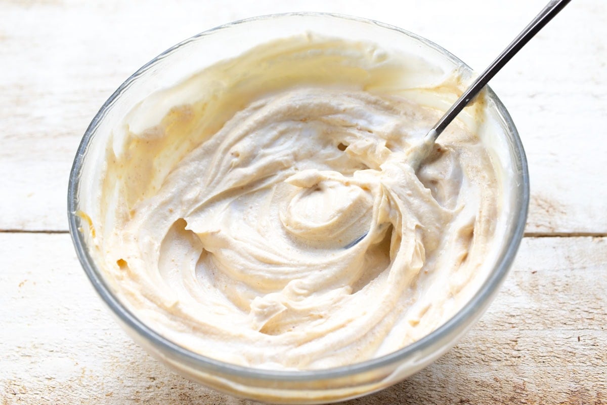 Peanut butter stirred into yogurt with a fork.