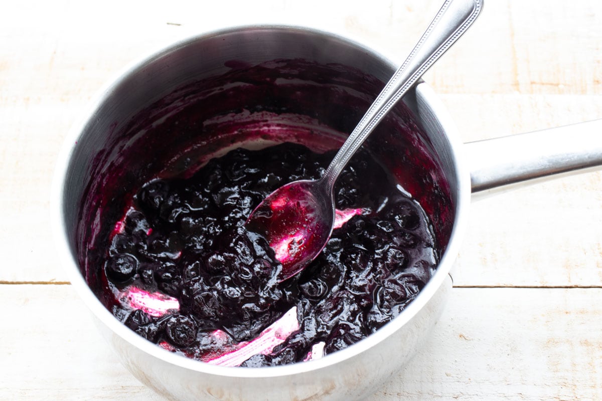 Blueberry sauce in a pot and a spoon.