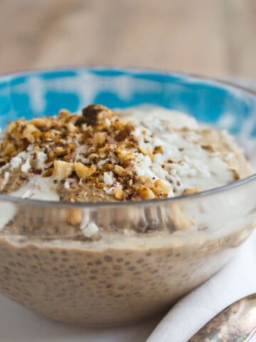 A glass bowl with coffee chia pudding topped with nuts