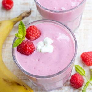Raspberry cottage cheese smoothie in a glass topped with fresh raspberries.