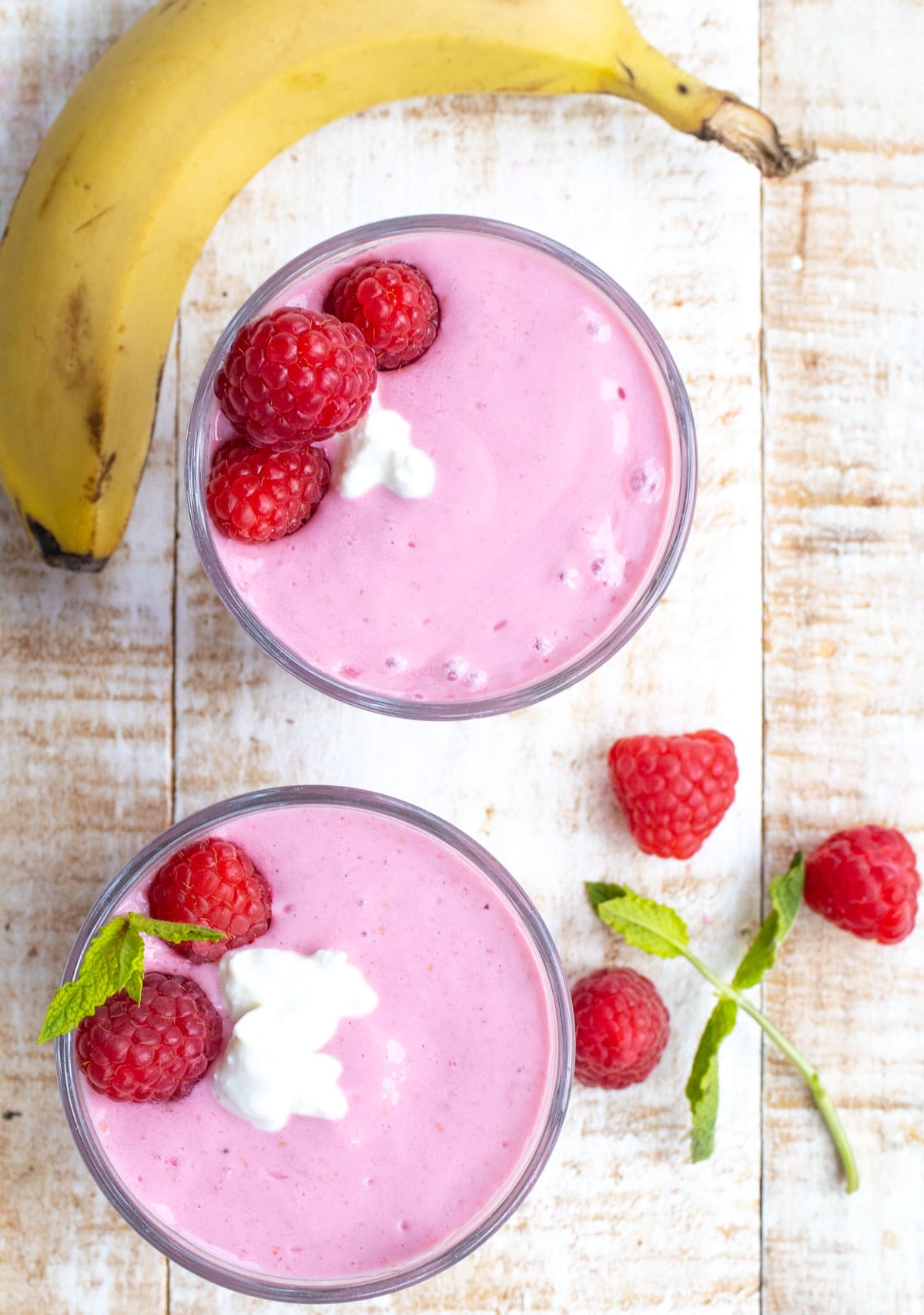 2 glasses with smoothie, decorated with raspberries.
