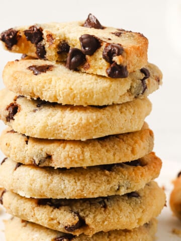 A stack of keto chocolate chip cookies topped with half a cookie.