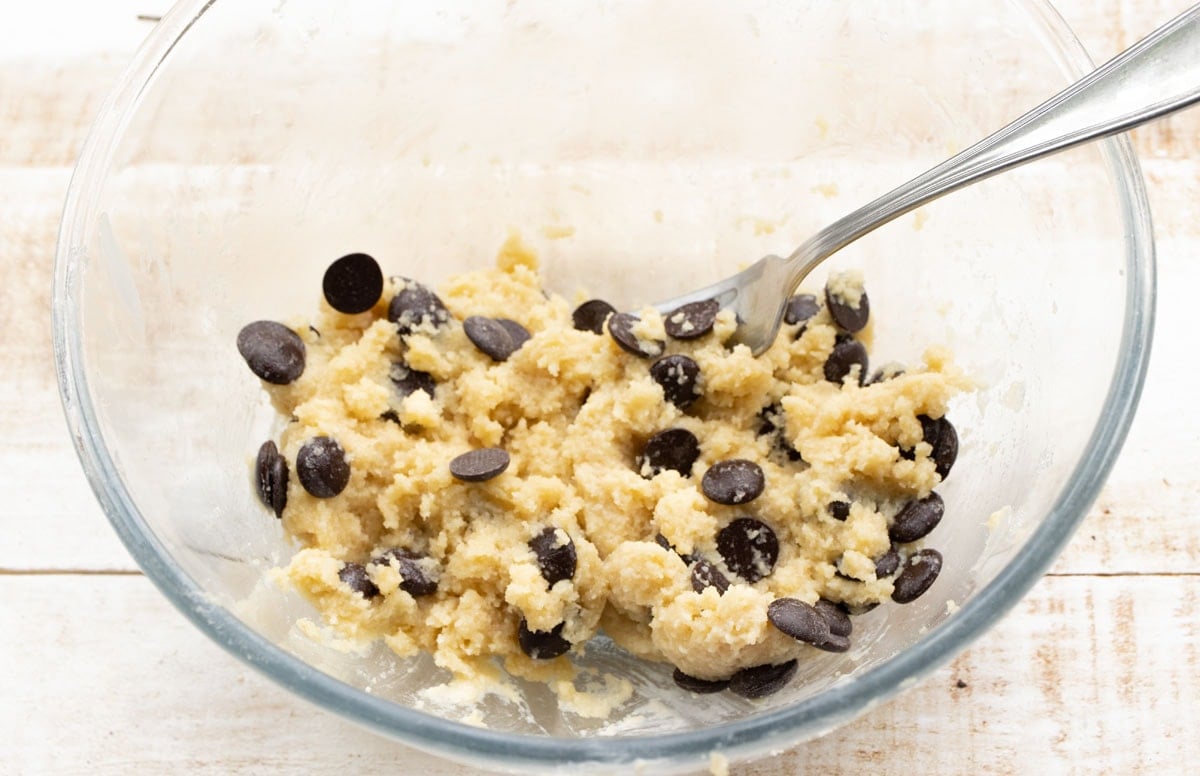 Cookie dough with chocolate chips in a bowl and a fork.