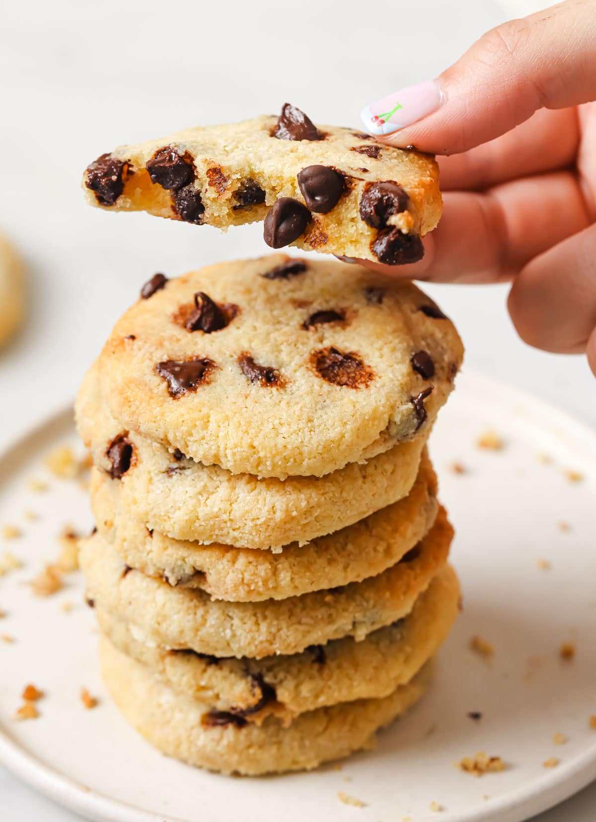 A stack of cookies and a hand lifting a cookie broken in half.