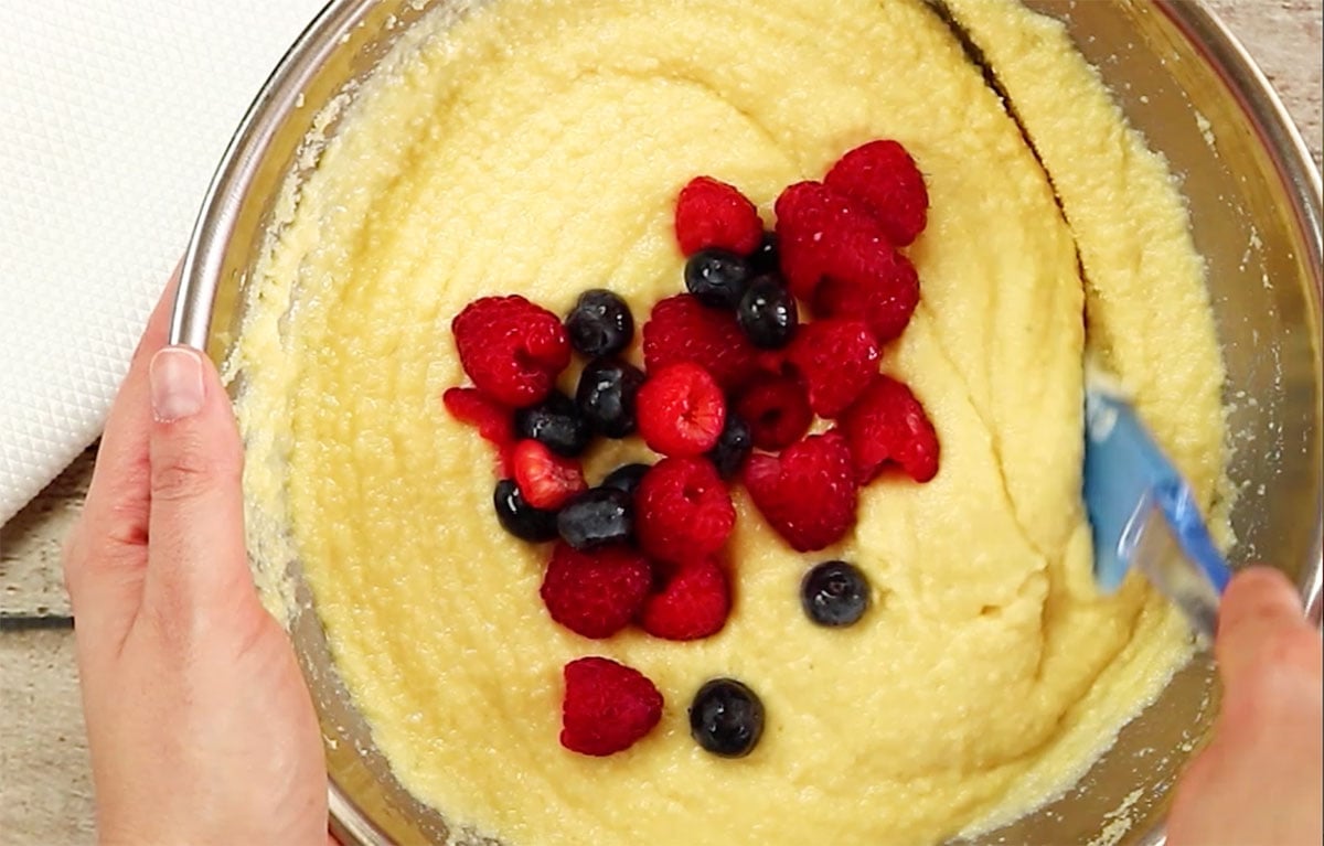 Stirring blueberries and raspberries into the batter.