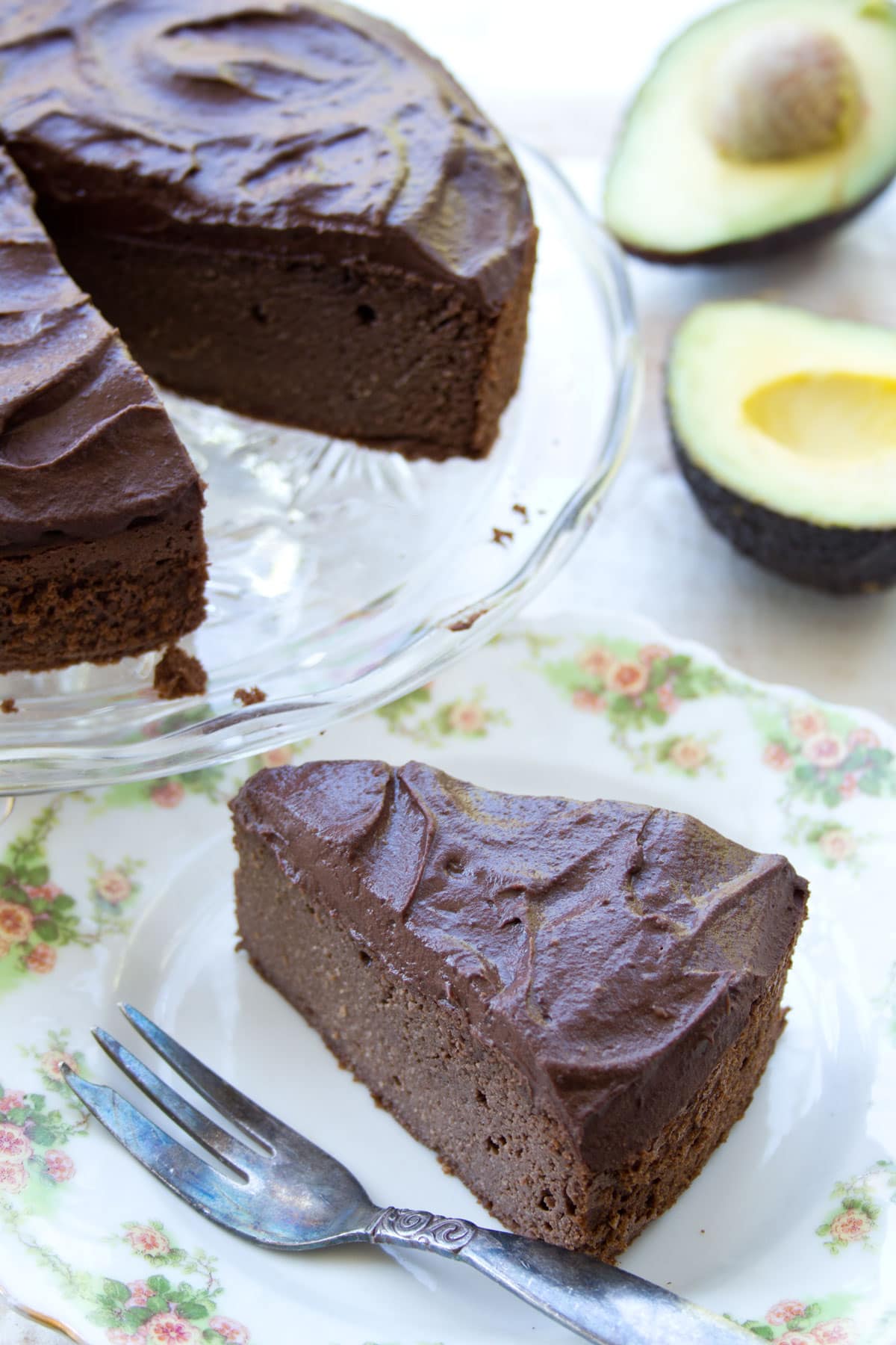 A slice of avocado chocolate cake on a plate with a fork.