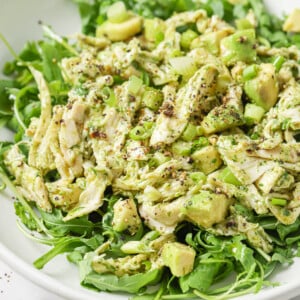 Avocado and chicken salad on a bed of lettuce topped with chopped spring onions.