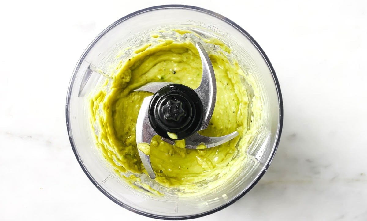 Avocado dressing in a food processor bowl.