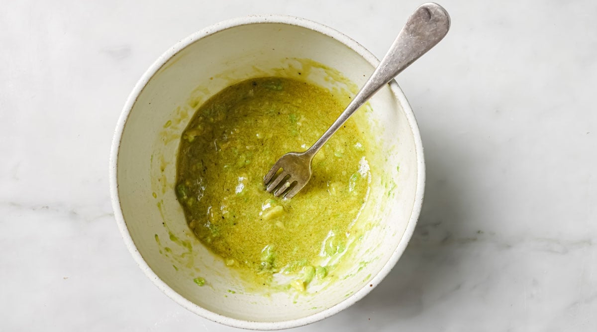 Dressing with mashed avocado in a bowl and a fork.