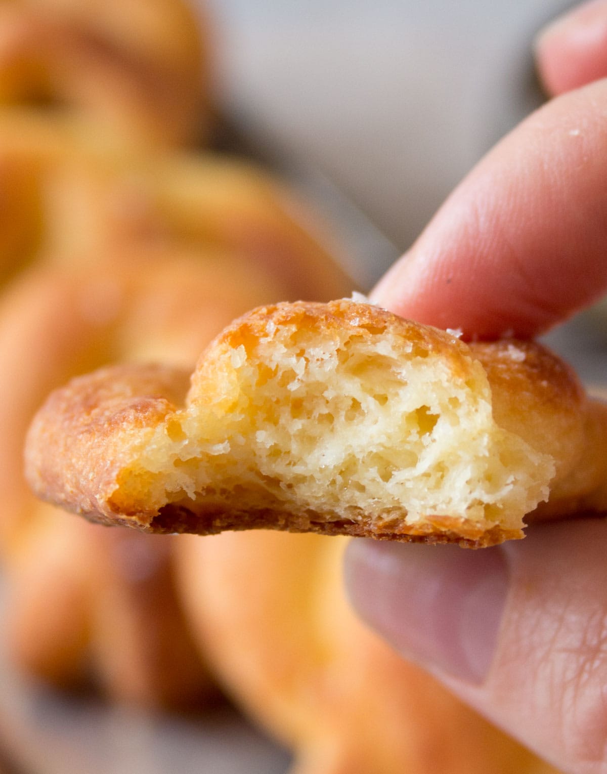 Hand holding a bitten pretzel, showing the inside.