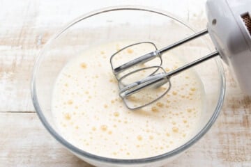 Whisked eggs in a bowl and an electric mixer.