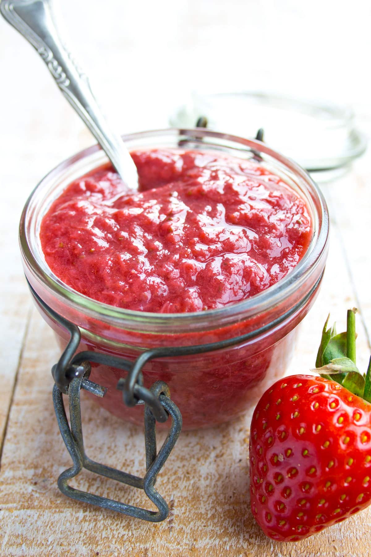 Sugar free strawberry jam in a jar with a spoon and a strawberry.
