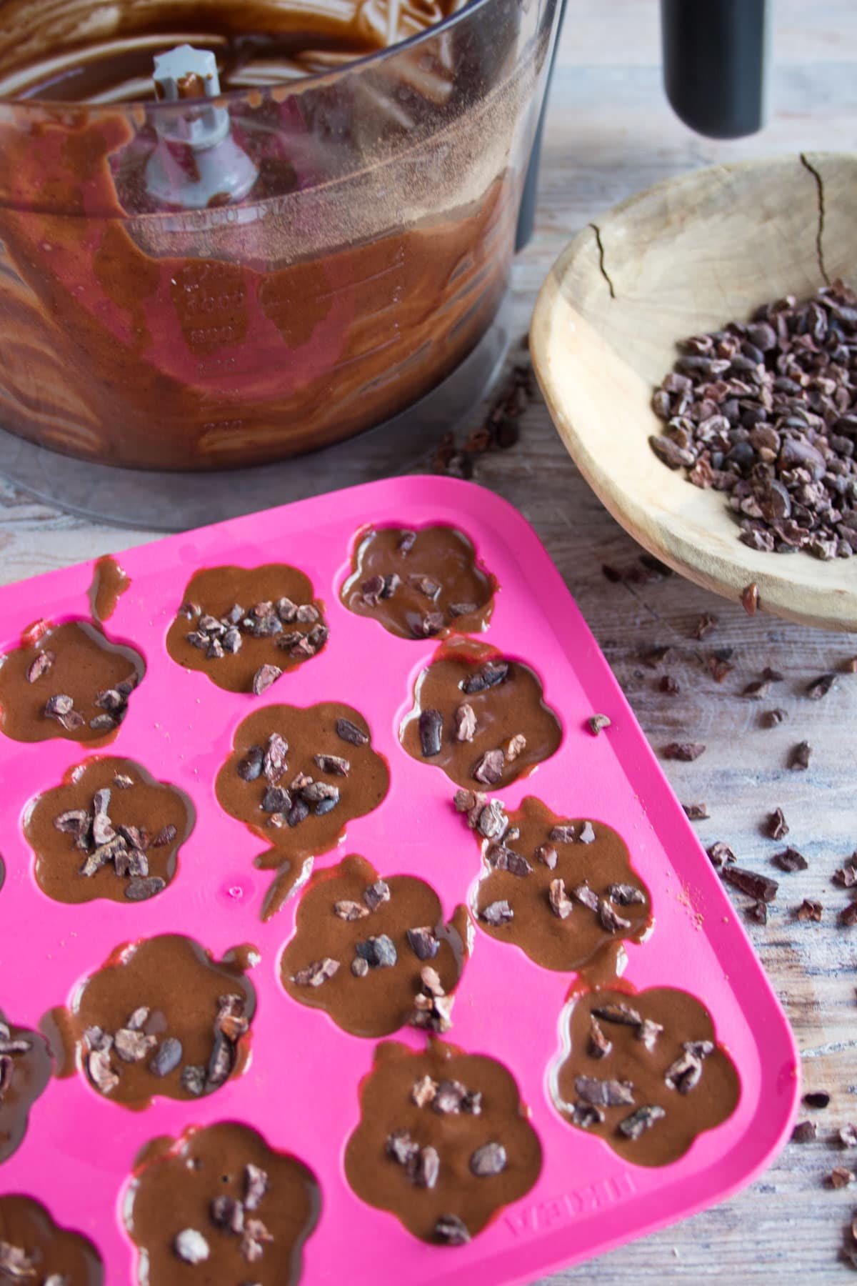 The chocolate mixture in a silicone ice cube tray, topped with cocoa nibs.