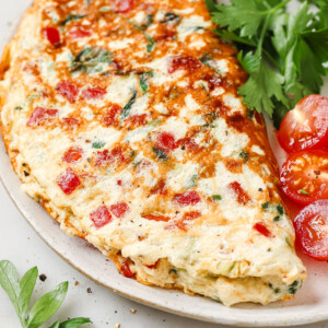 Egg white omelette on a plate with tomatoes and parsley.