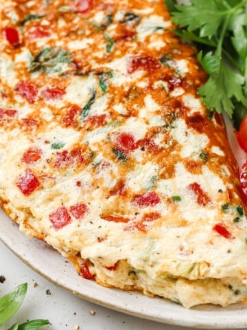Egg white omelette on a plate with tomatoes and parsley.