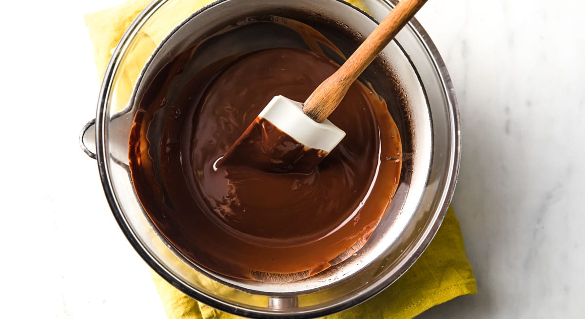 Melted chocolate in a double boiler and a spatula.