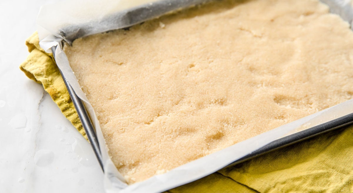 Almond flour crust in a pan lined with parchment paper.