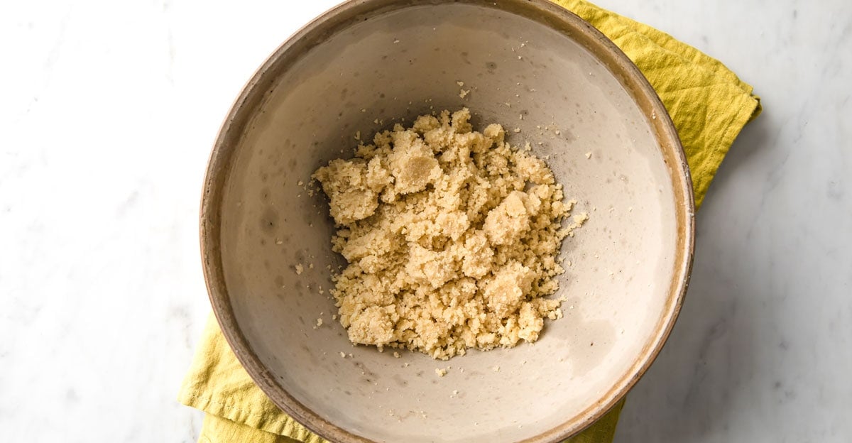 Almond flour dough crumbles in a mixing bowl.