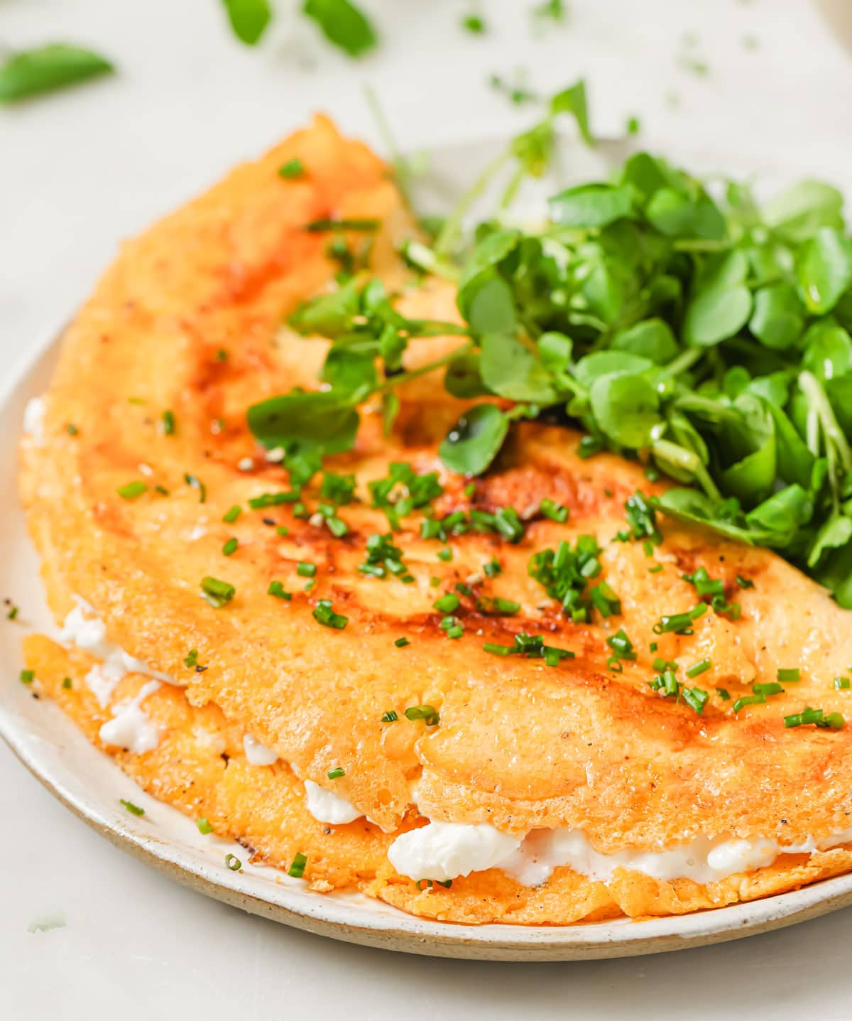 A cottage cheese omelette filled with cottage cheese and topped with chopped chives.