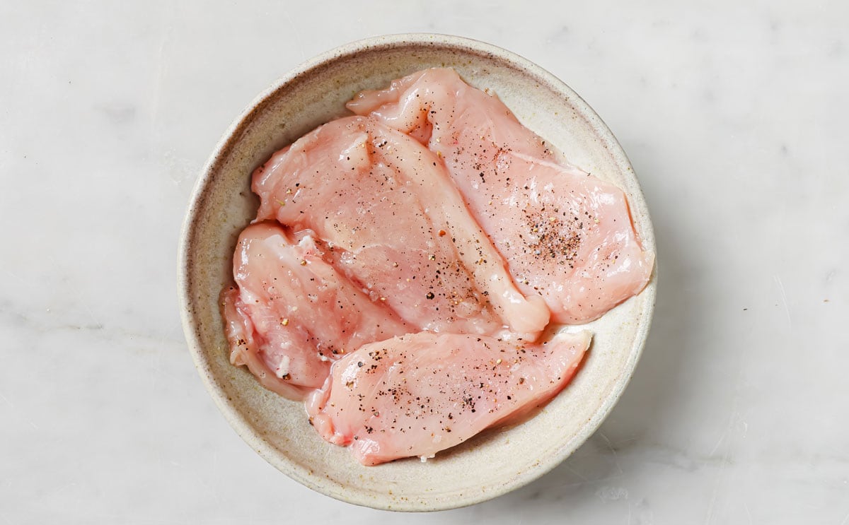 Seasoned chicken fillets in a bowl.