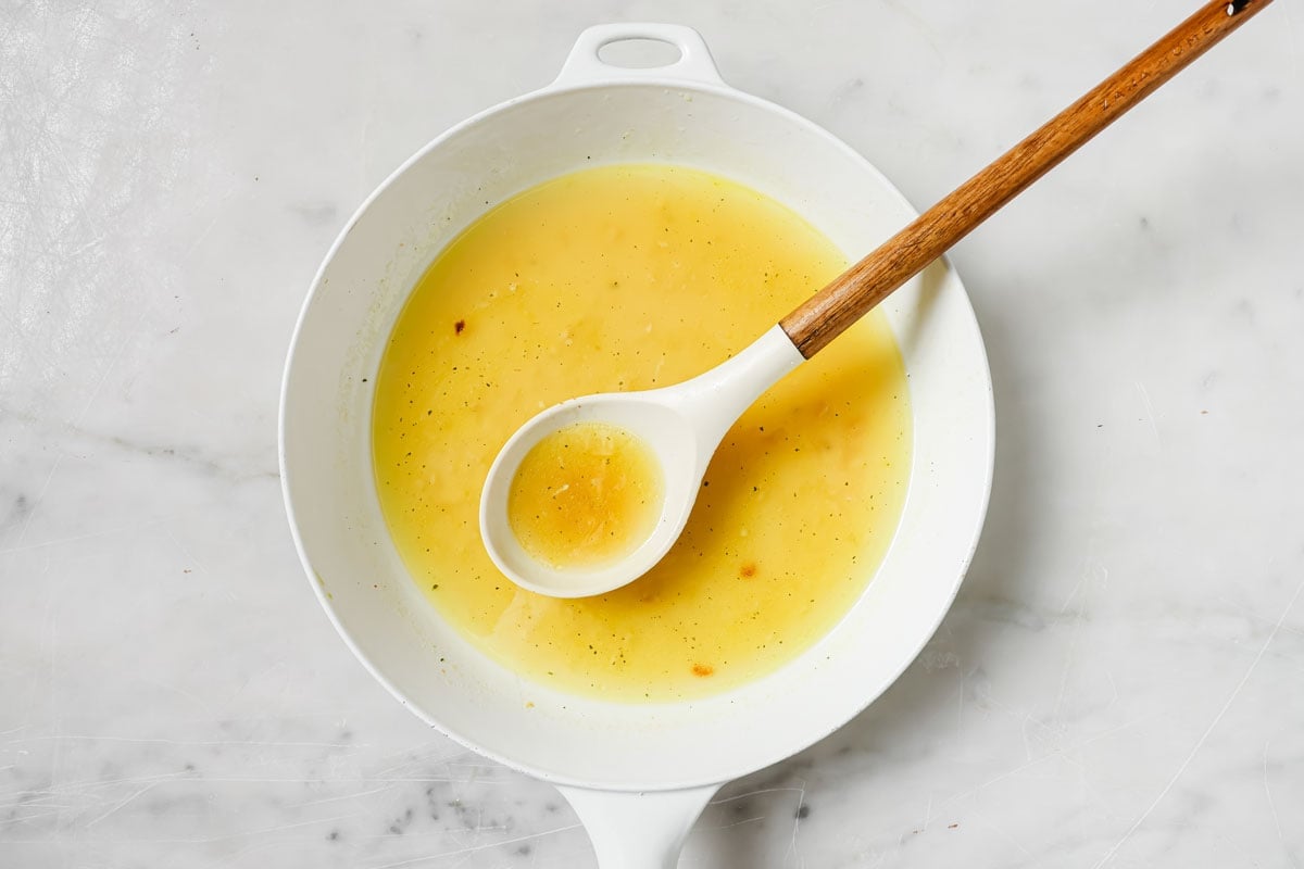 Chicken stock in a pan with a spatula.