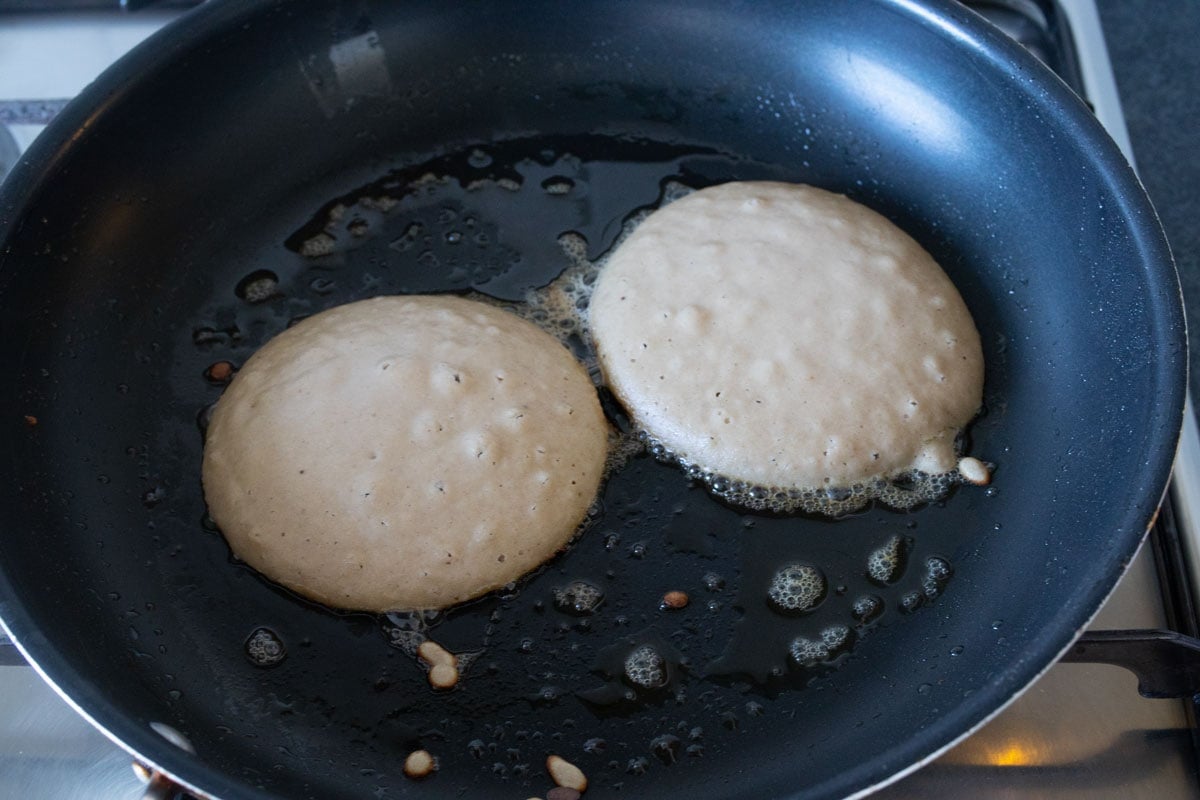 Pancake batter in a pan with air bubbles.