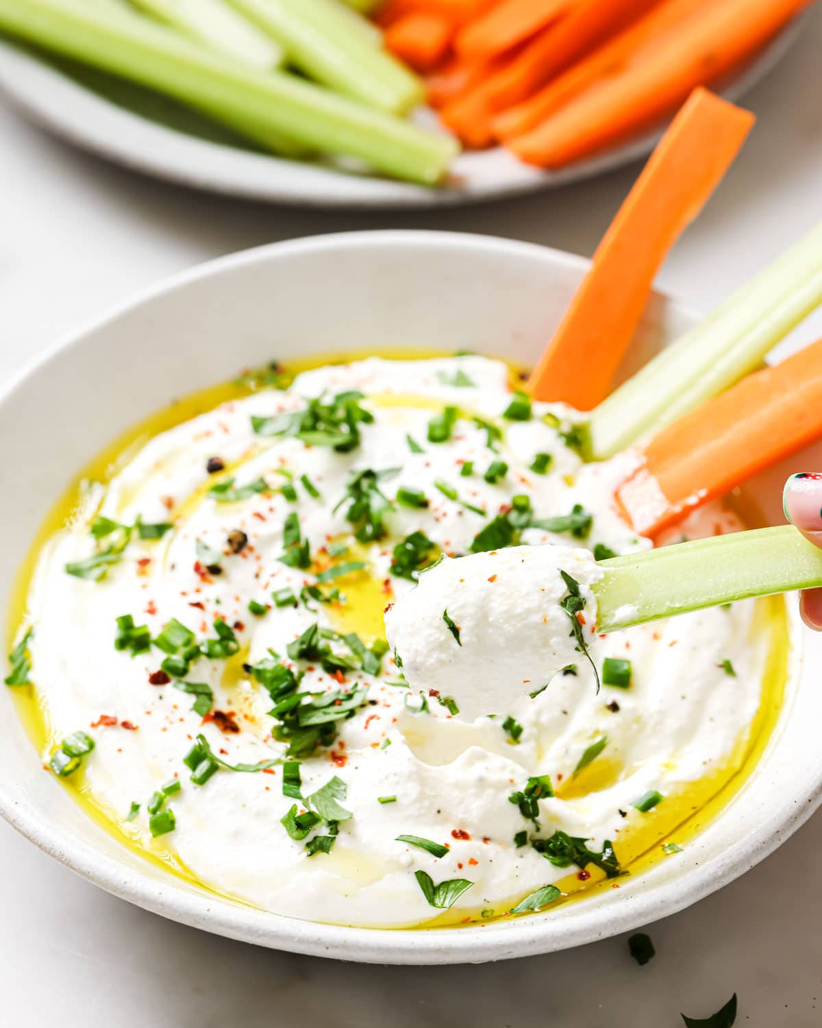 Blended cottage cheese topped with olive oil, pepper flakes and chopped herbs and vegetable sticks for dipping.