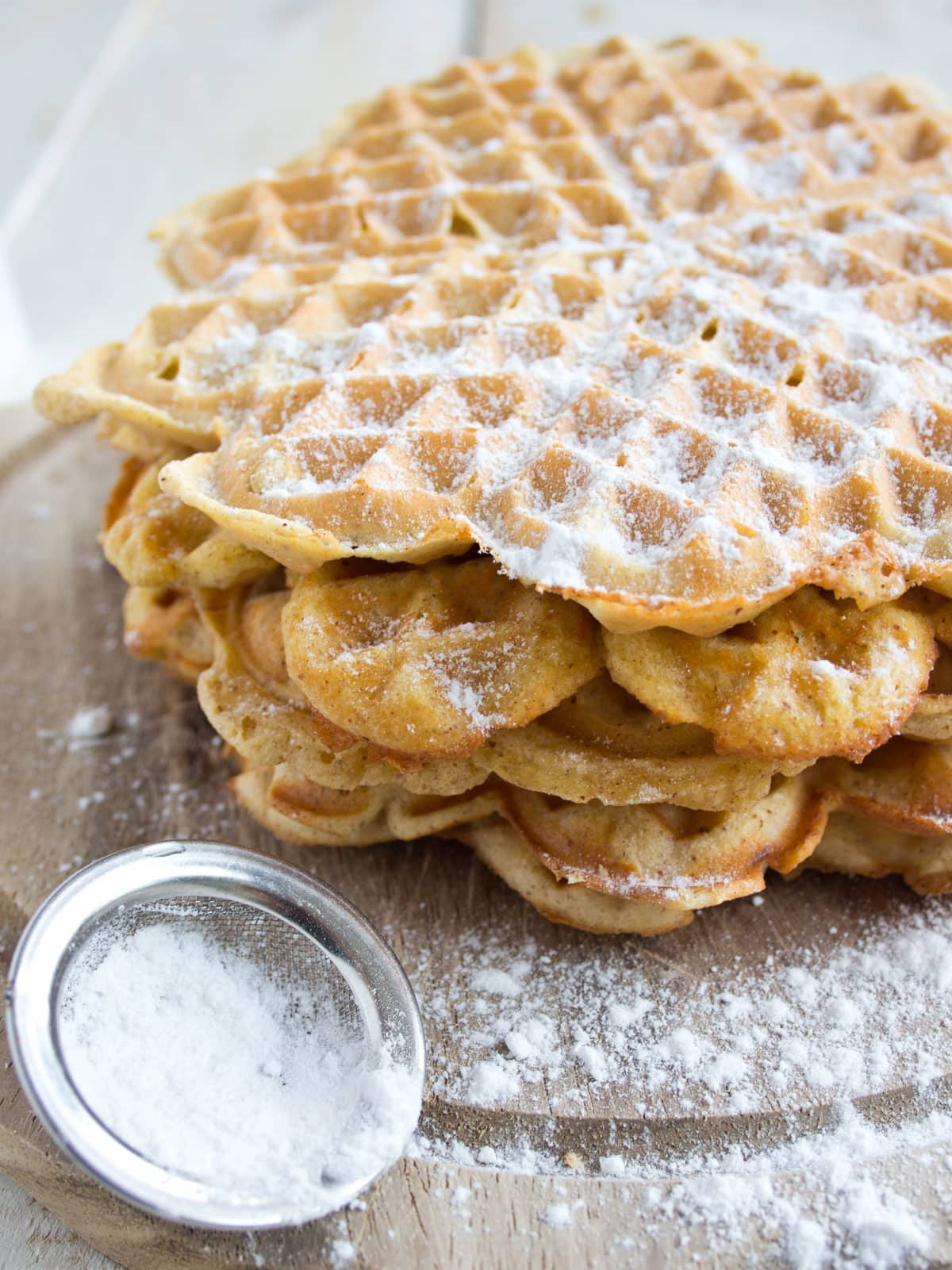A stack of waffles dusted with powdered sweetener.