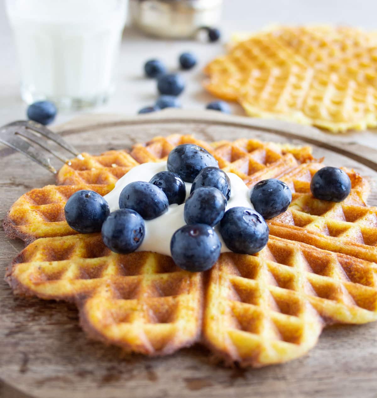 A heart-shaped waffle topped with sour cream and blueberries.