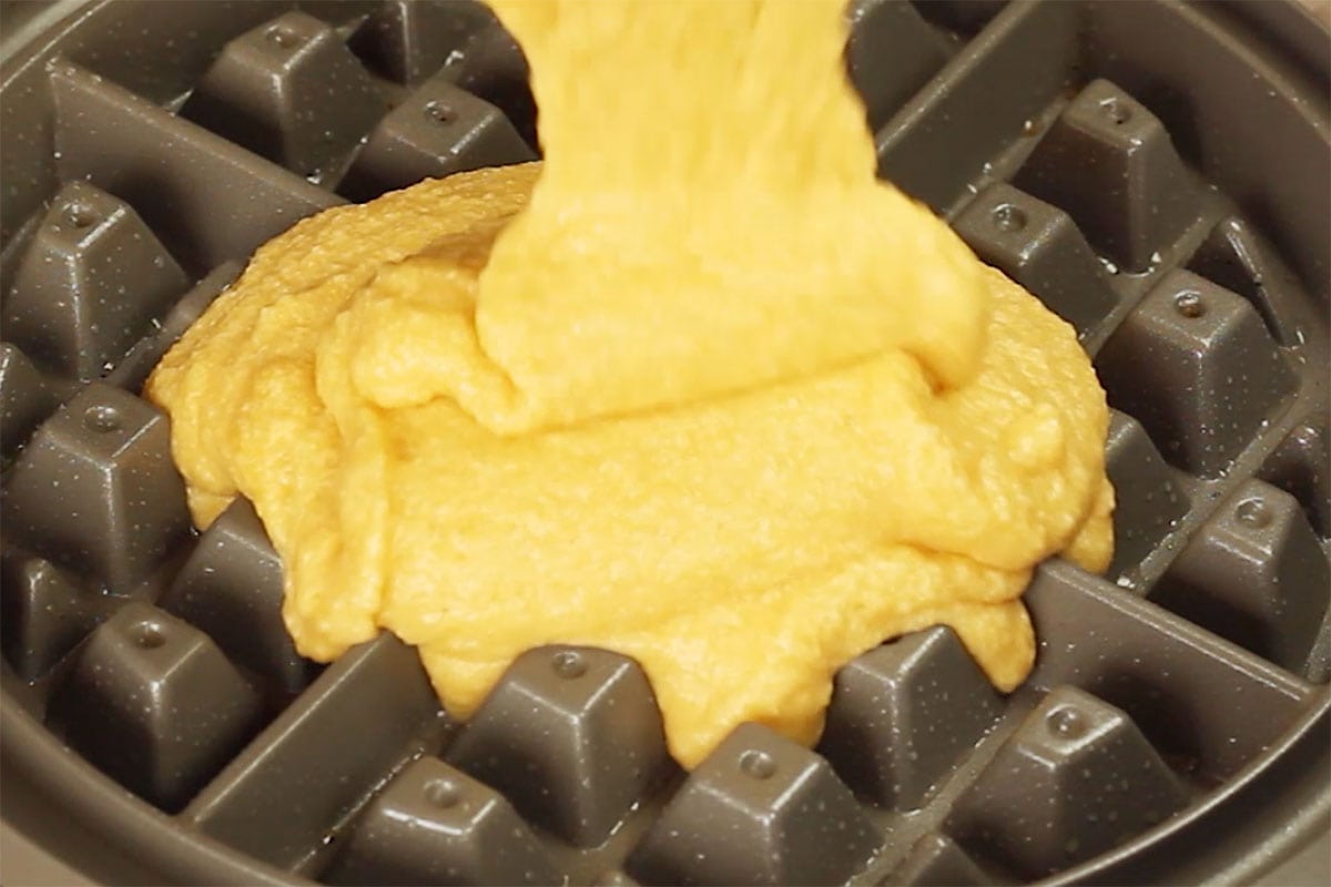 Pouring batter into the waffle iron.