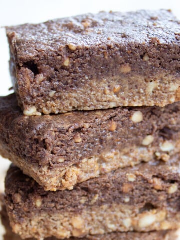 A stack of homemade peanut butter protein bars with a peanut butter and a chocolate layer.
