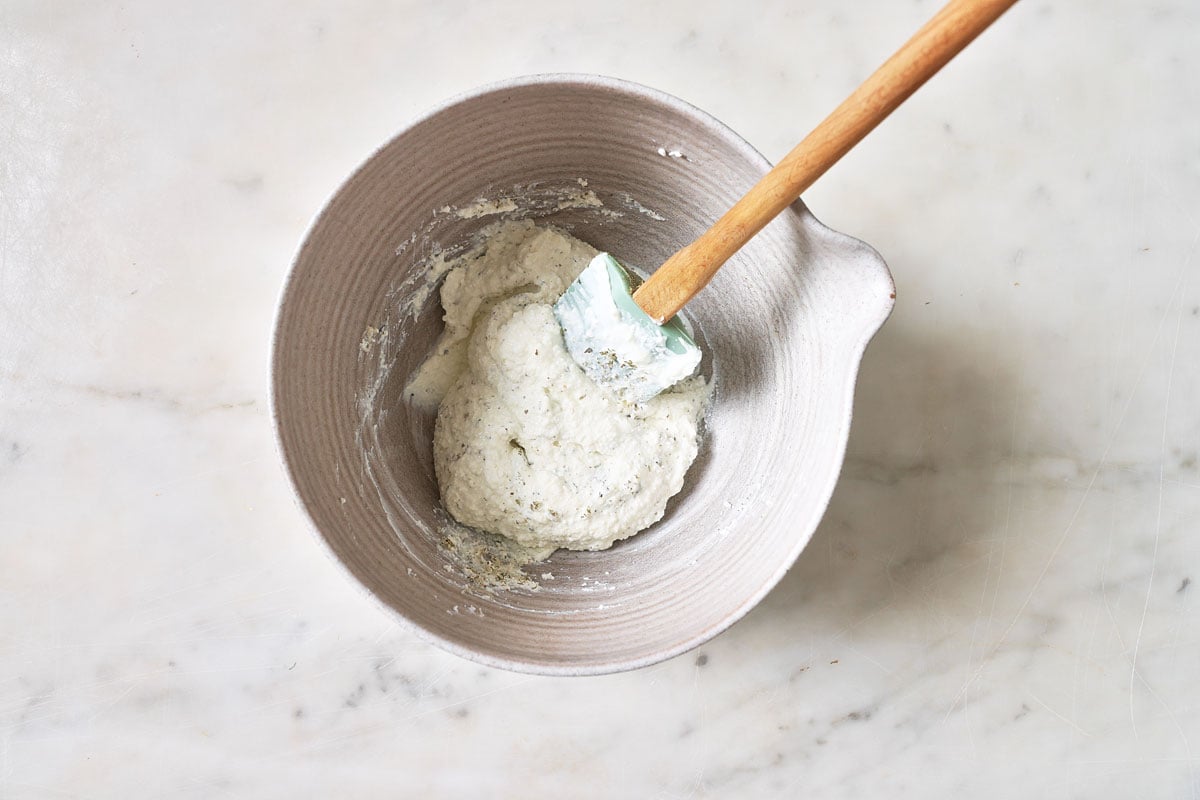 Cottage cheese mixture in a mixing bowl and a spatula.