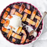 A berry pie with a latice crust topping and a spoon.