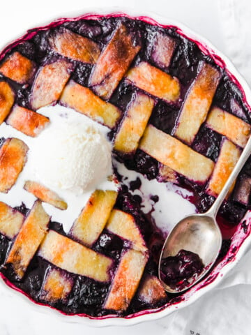 A berry pie with a latice crust topping and a spoon.
