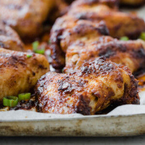 Crispy bbq chicken wings in a pan with chopped spring onions.