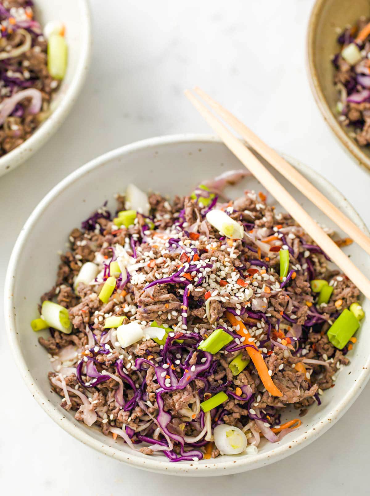 Ground beef and cabbage in a bowl with chopsticks.