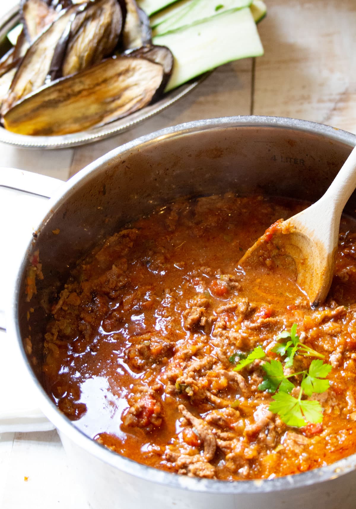 A pot with Bolognese sauce and a wooden spoon.