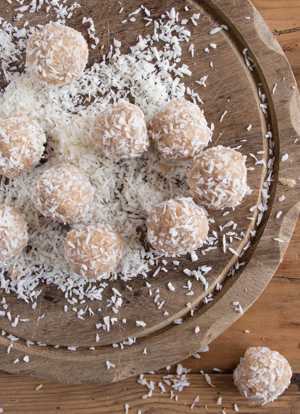 Bliss ball coated in desiccated coconut on a wooden board.