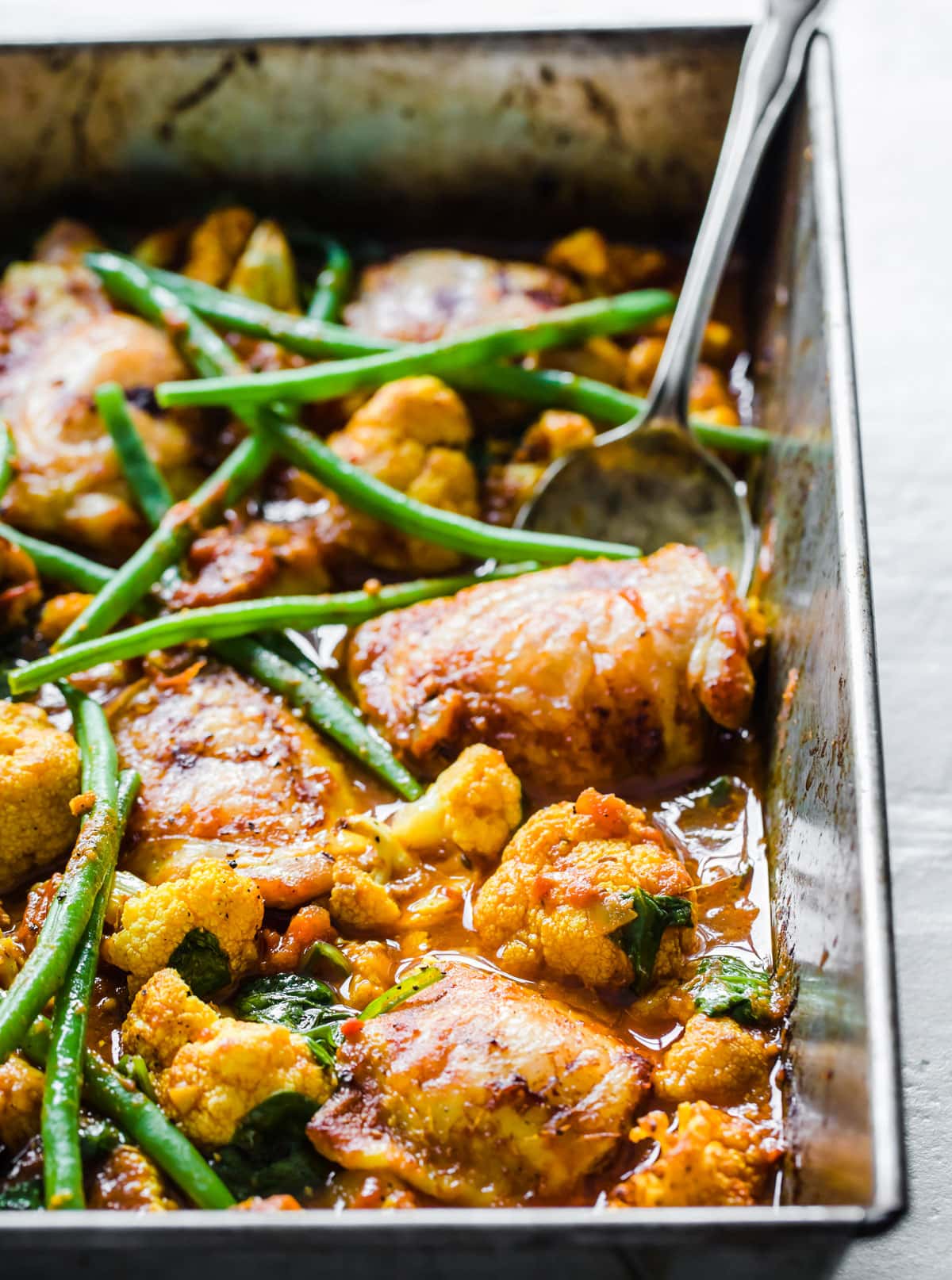 Roasted chicken thighs and cauliflower florets in a curry sauce and green beans.