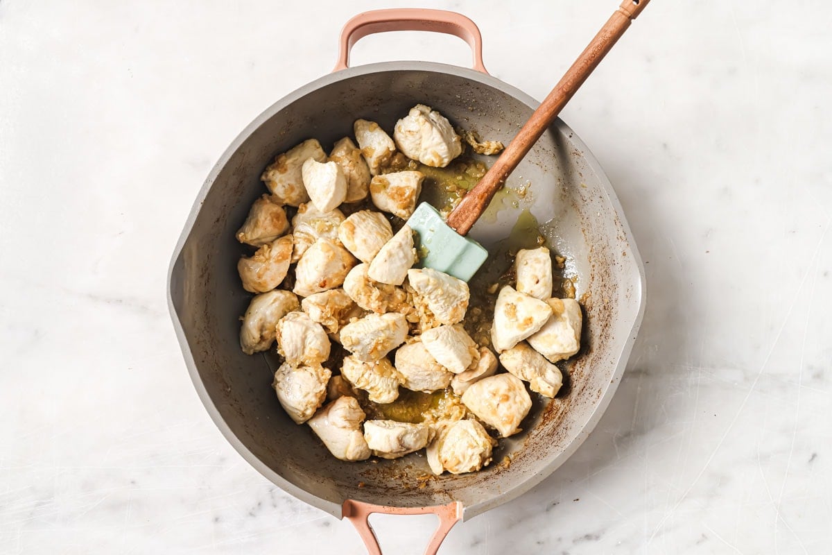Frying cubed chicken breast in a pan.