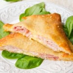 Keto hot pockets sliced diagonally and arranged on a bed of spinach leaves.