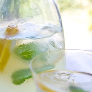 Sugar free, healthy ginger ale in a glass jug with ice cubes, mint leaves and lemon slices.