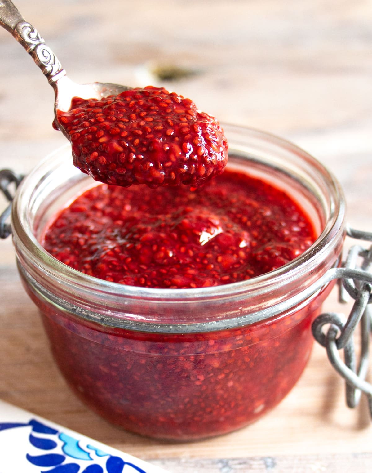 A glass jar with sugar free raspberry jam and a spoon.