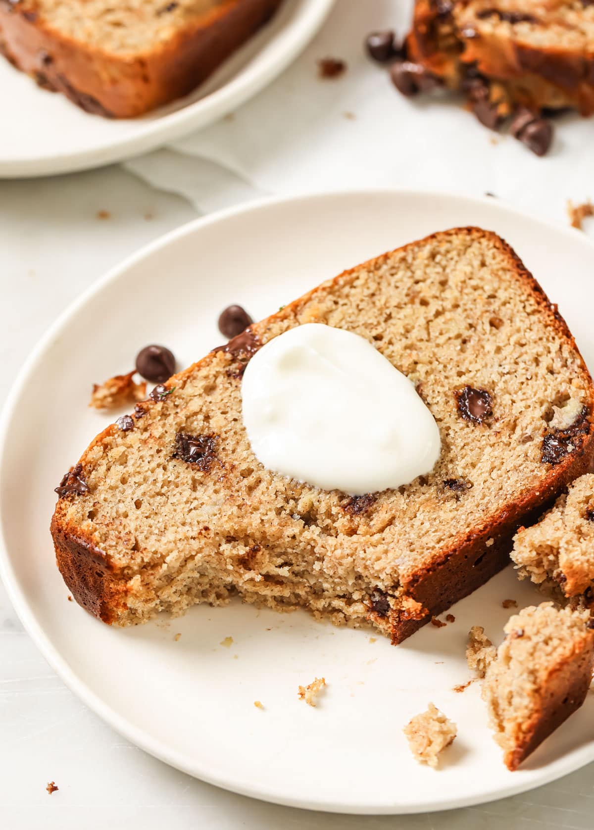 A slice of banana bread on a plate with a dollop of yoghurt.